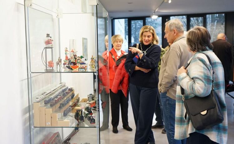 Herr Hübner mit Besucherinnen vor der Vitrine mit Sammlungsobjekten der Firma Märklin : Zum Vergrößern auf Bild klicken